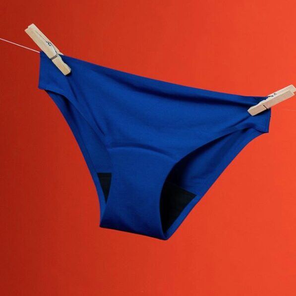 Culotte menstruelle Smoon bleue suspendue sur fond orange